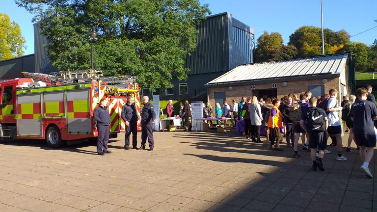 people gathered, firemen standing in front of fire engine