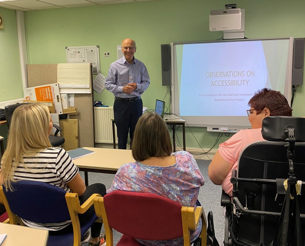 Tony Crowhurt stands at the front of the room. Three women are sat listening. whiteboard displays words Observations on Accessibility